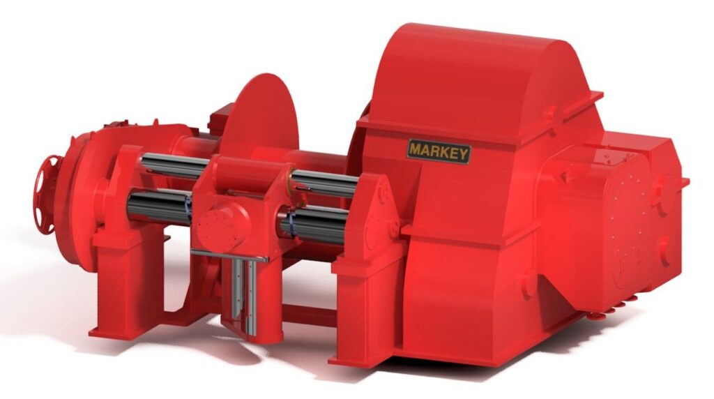 bright red industrial winch made by Markey. The winch is compact yet robust, featuring cylindrical components and hydraulic cylinders designed for heavy-duty tasks. The Markey logo is prominently displayed on the side, indicating the brand of the machinery. This equipment is likely used for towing or pulling operations in marine or industrial settings.